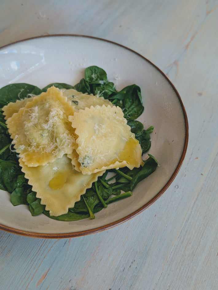 Spinach & Ricotta Ravioli served on fresh spinach with grated cheese