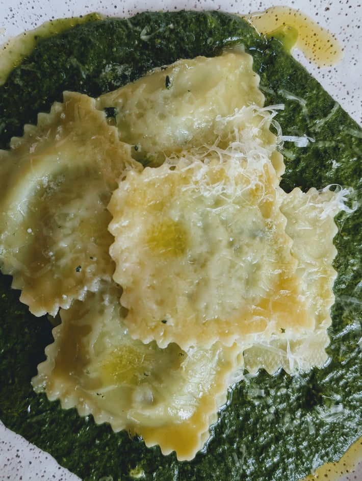 Ravioli on spinach sauce with grated cheese