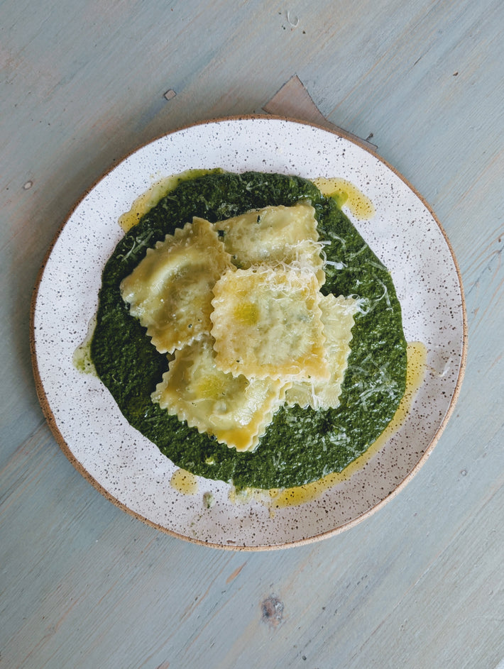 Spinach & Ricotta Ravioli served on pesto sauce with grated cheese