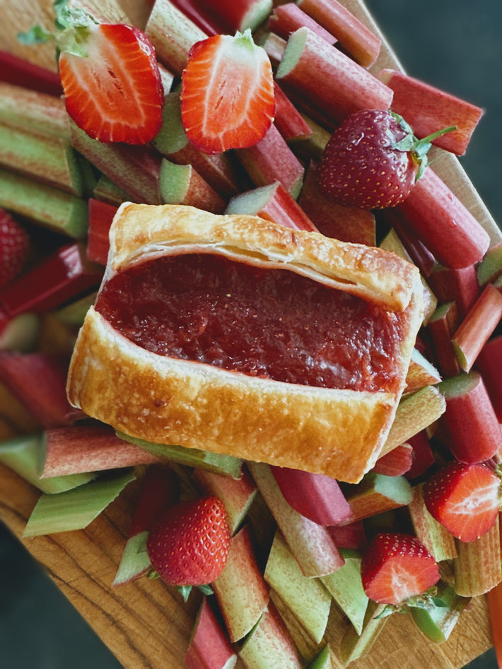 Strawberry Rhubarb Turnover surrounded by fresh strawberries and rhubarb