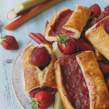 Angled view of Strawberry Rhubarb Turnovers (4-pack) with golden flaky crust and strawberry-rhubarb filling