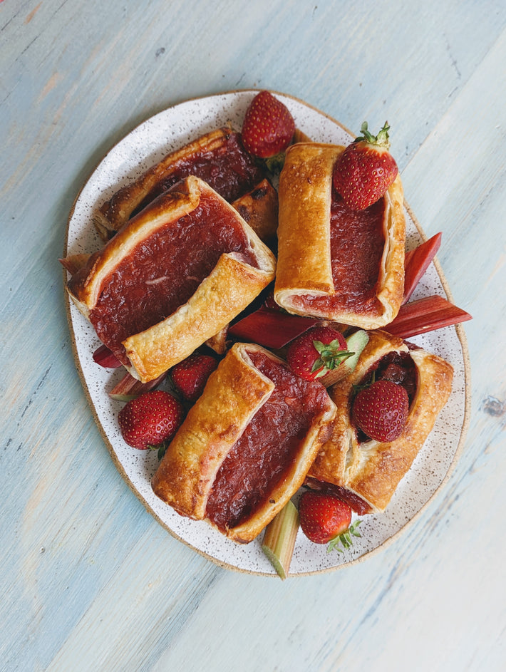 Strawberry Rhubarb Turnovers on a plate with strawberries and rhubarb