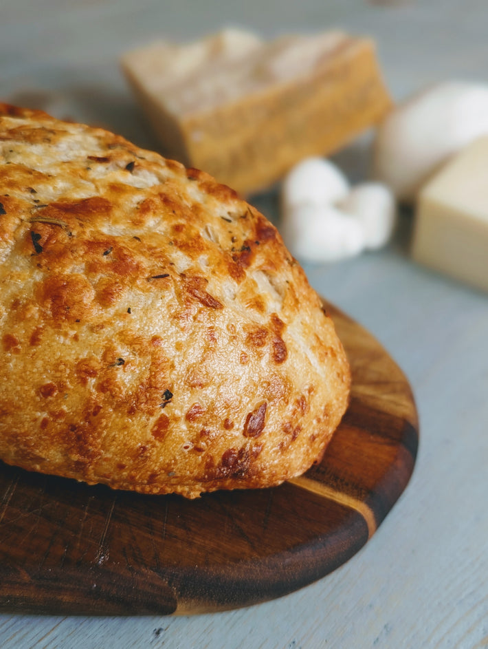 Sourdough 3-Cheese Loaf on a wooden board with cheese in the background