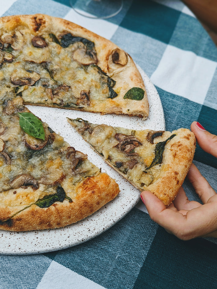 Slice of Slow-Fermented Veggie Pizza topped with mushrooms and spinach
