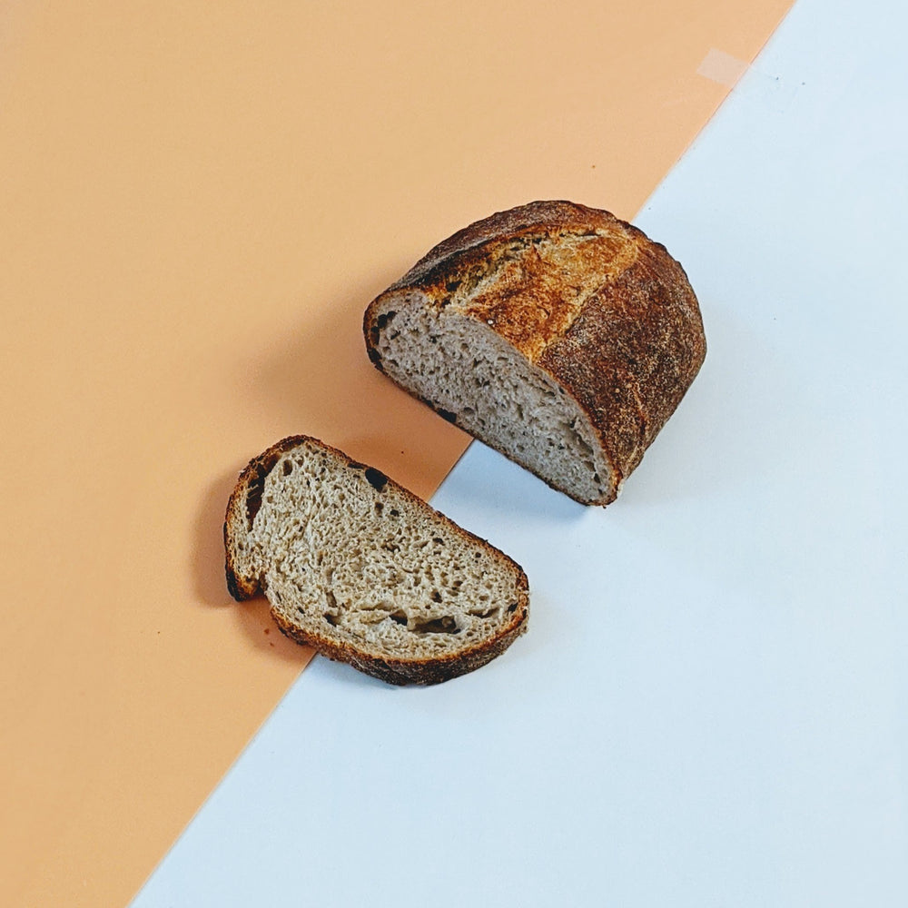 Sliced artisan sourdough loaf on a diagonal peach-and-white background