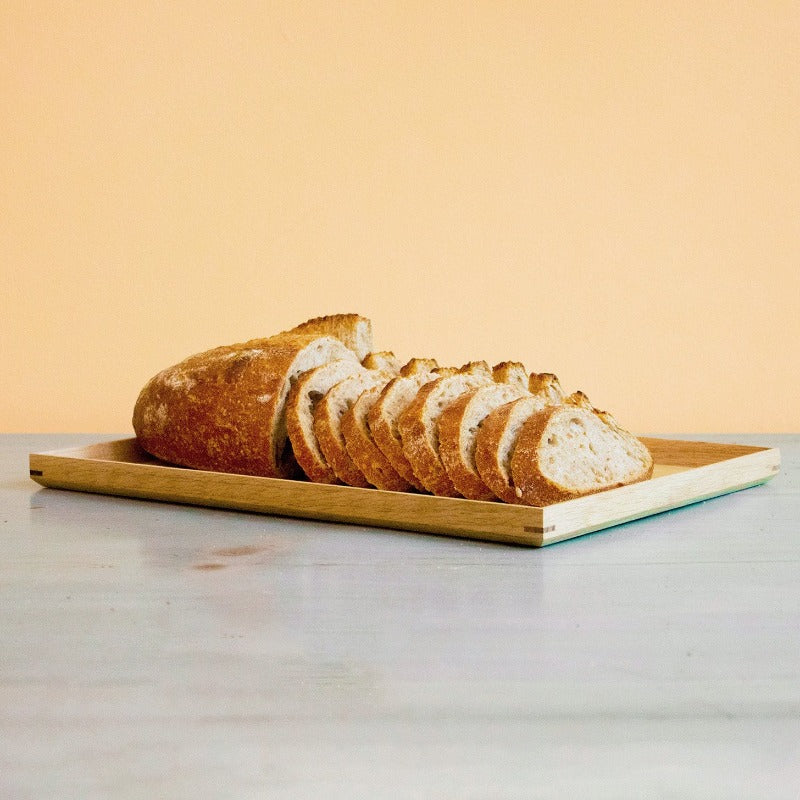 Sliced sourdough whole wheat loaf on a wooden board against a light background