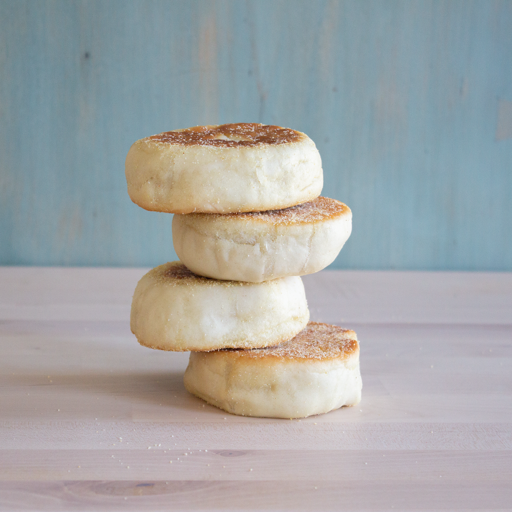 Four stacked English muffins on a wooden surface