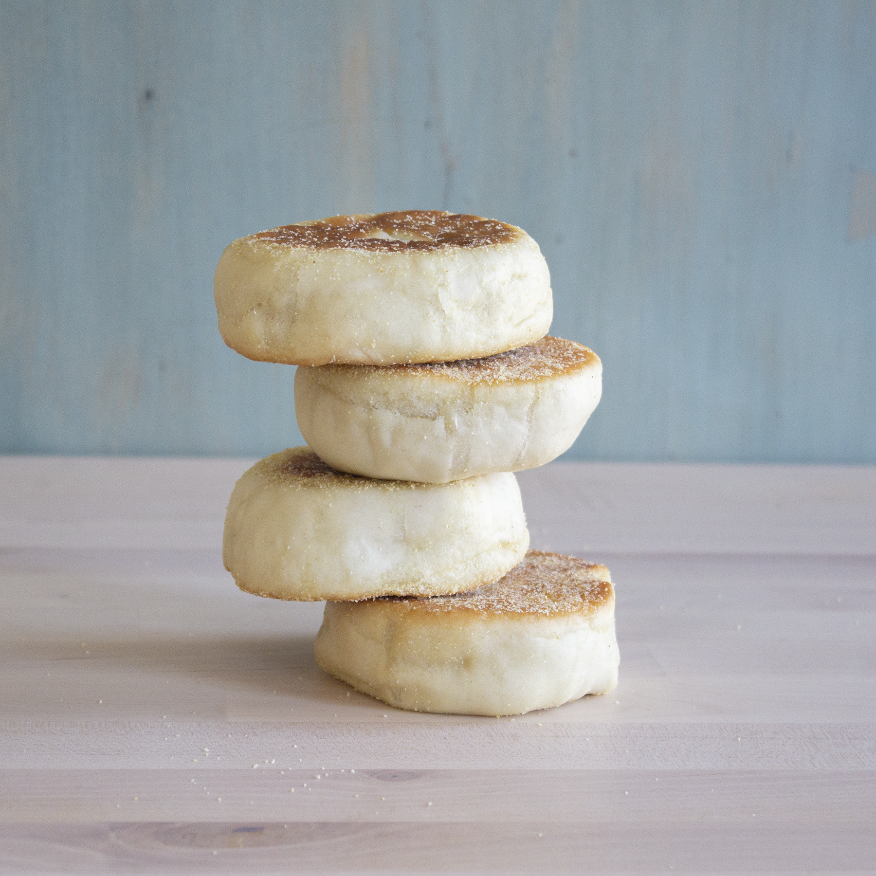 Four stacked English muffins on a wooden surface