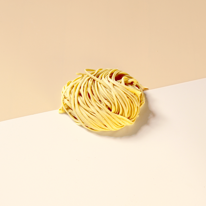 Gluten-Free Fresh Linguine ball on a white surface with beige background.