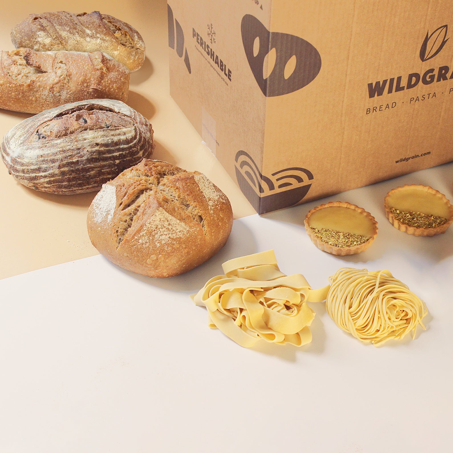 A variety of breads, pasta, and pastries next to a Wildgrain box.
